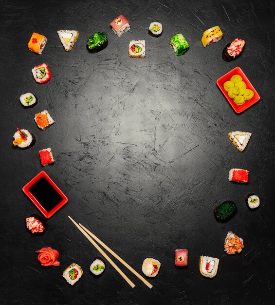 Fondo de sushi. Vista superior de sushi japonés y palillos sobre fondo negro