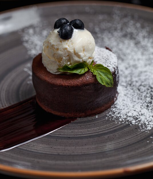 Una fondue de chocolate con bola de helado y bayas del bosque en la parte superior