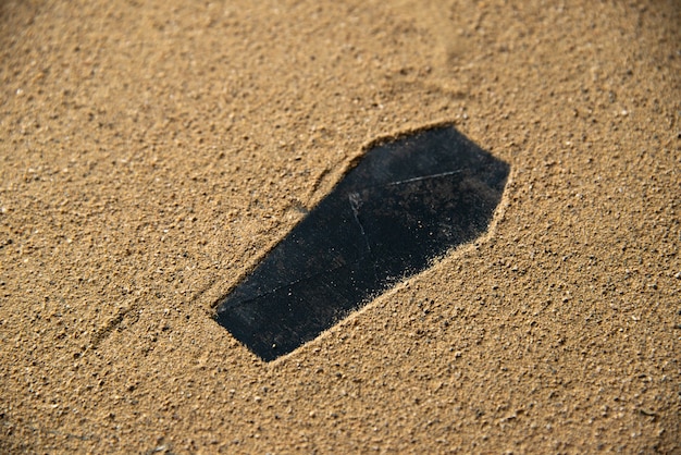 Foto gratuita forma de ataúd negro hecho en la arena