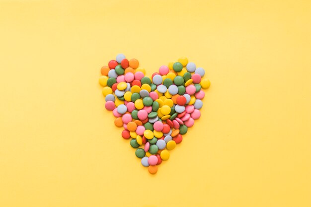 Forma de corazón hecha con gemas dulces sobre fondo amarillo