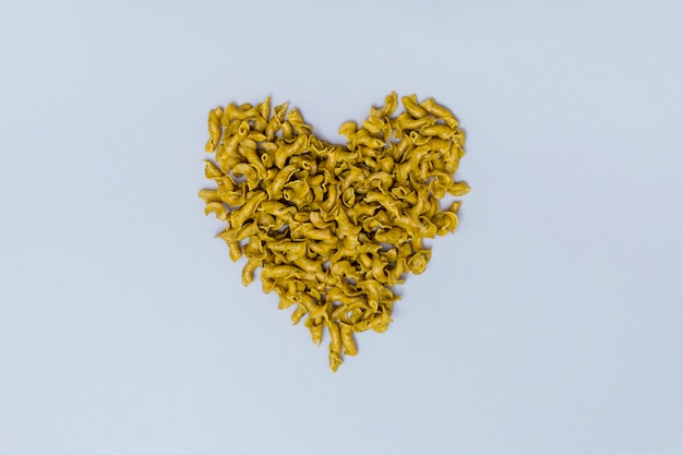Forma de corazón hecha de pasta cruda italiana sobre fondo gris