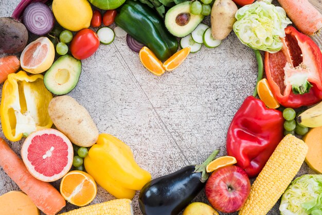 Forma de corazón hecha con verduras de colores sobre fondo texturizado