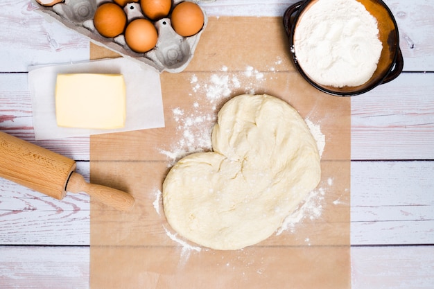 La forma del corazón hizo la masa amasada con ingredientes en tablones de madera.