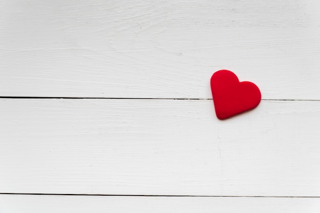 Forma de corazón rojo suave en tablón de madera blanco