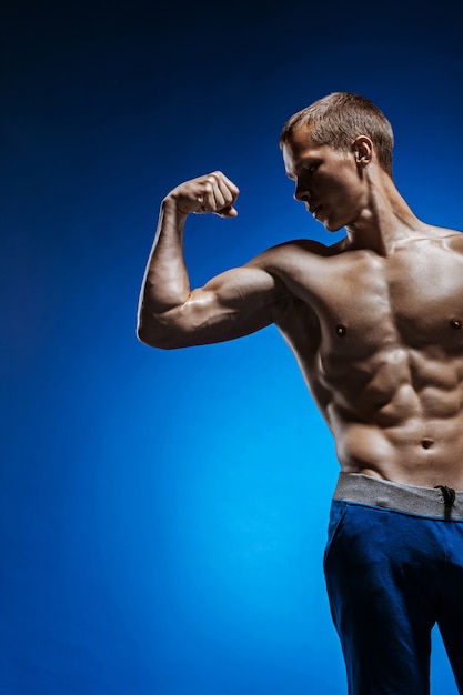 Foto gratuita forma joven con hermoso torso en la pared azul