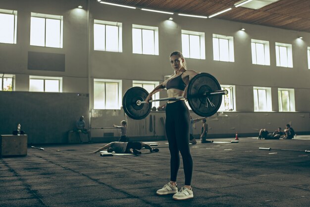 Forma joven levantando pesas ejercitándose en un gimnasio