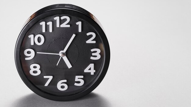 Forma redonda reloj despertador negro sobre fondo gris