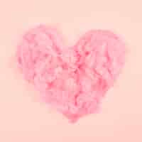 Foto gratuita forma suave rosada del corazón de la pluma en fondo coloreado melocotón