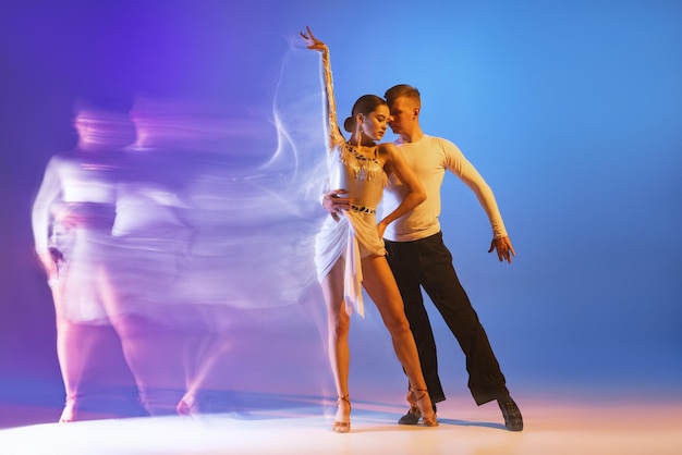 Formación de dos jóvenes bailarines profesionales aislados sobre la pared azul y púrpura degradado