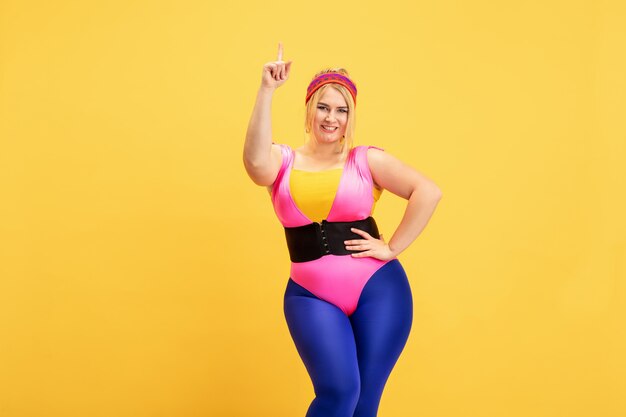 Formación de joven caucásica plus size modelo femenino en amarillo