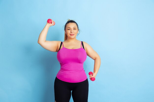 Formación de joven caucásica plus size modelo femenino en espacio azul