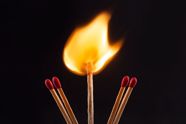 Fósforos de madera ardiendo con fondo oscuro