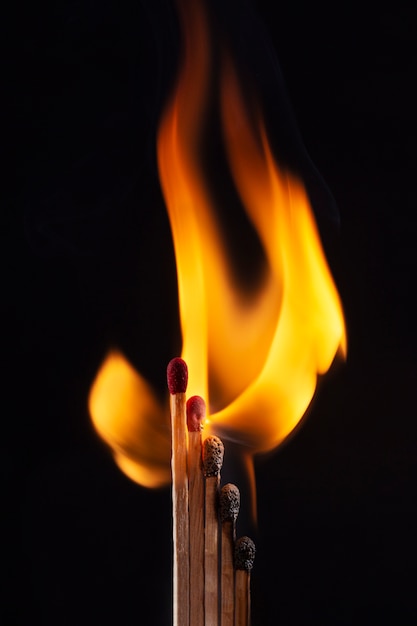 Fósforos de madera ardiendo con fondo oscuro