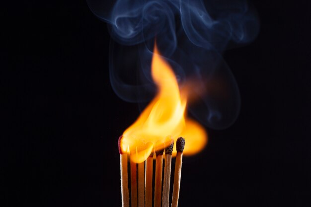 Fósforos de madera ardiendo con fondo oscuro