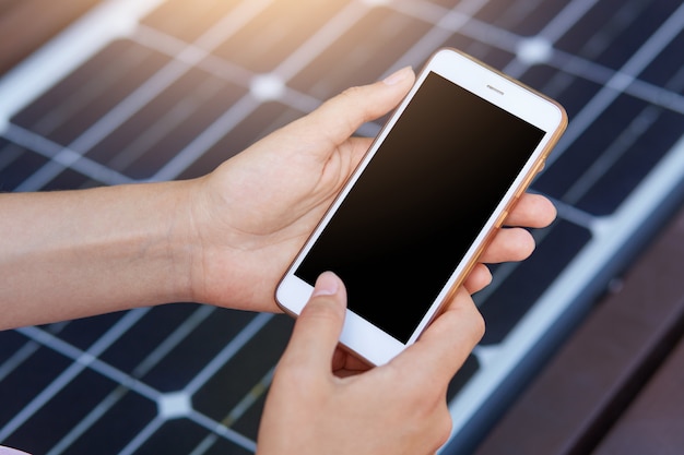 Foto al aire libre de una persona sin rostro que acosa el teléfono móvil a través de USB. Carga pública en banco con panel solar en calle de la ciudad