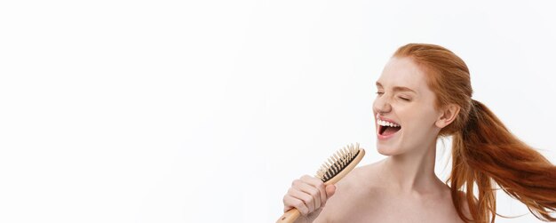 Foto gratuita foto de una alegre y sonriente mujer joven de jengibre pecoso peina su largo cabello rojo alegre de prepararse para da