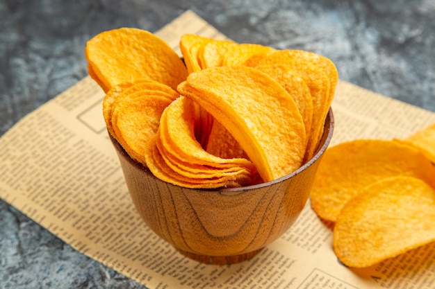 Foto de alta resolución de deliciosas patatas fritas caseras en periódico sobre mesa gris