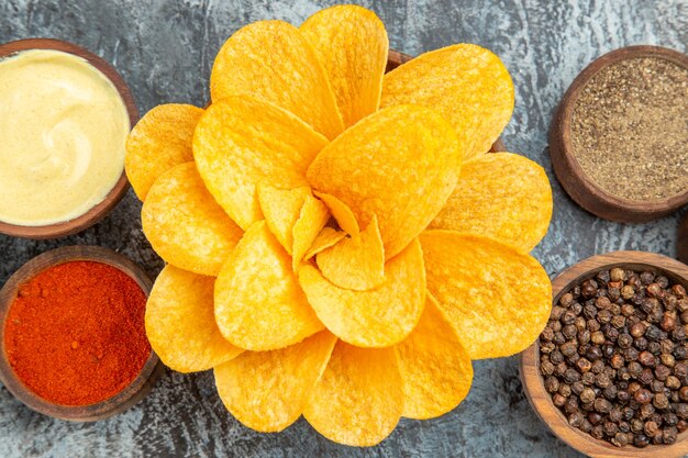 Foto de alta resolución de papas fritas caseras decoradas con forma de flor en un recipiente marrón sobre tabla gris