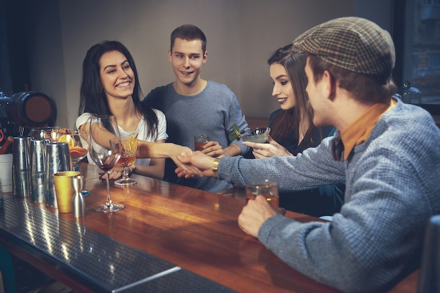 Foto de amigos alegres en el bar o en el pub comunicándose entre ellos