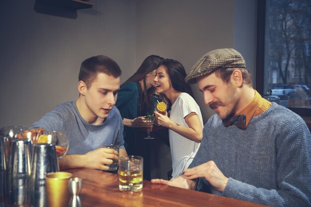 Foto de amigos alegres en el bar o en el pub comunicándose entre ellos