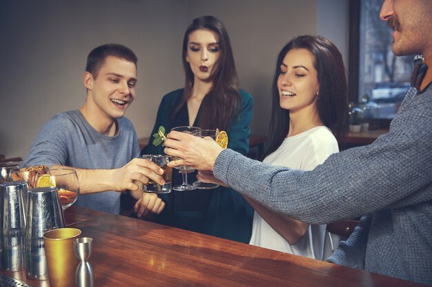 Foto de amigos alegres en el bar o en el pub comunicándose entre ellos