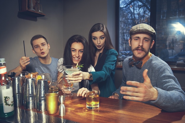 Foto de amigos alegres en el bar o en el pub comunicándose entre ellos