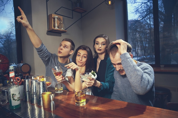 Foto de amigos alegres en el bar o en el pub comunicándose entre ellos
