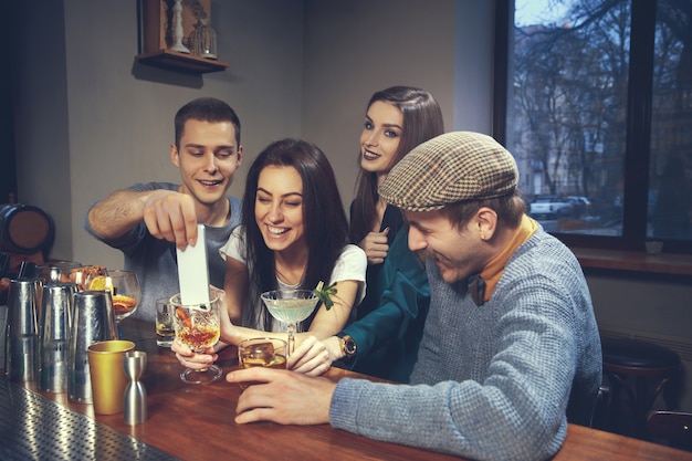 Foto de amigos alegres en el bar o en el pub comunicándose entre ellos