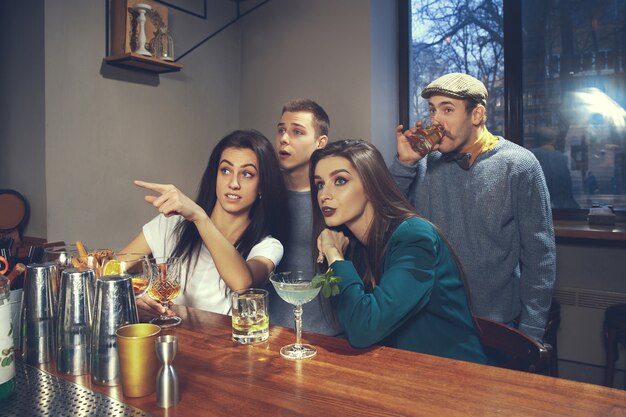 Foto de amigos alegres en el bar o en el pub comunicándose entre ellos