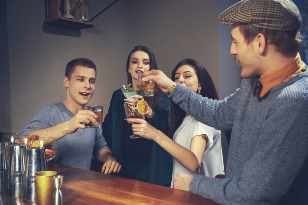 Foto de amigos alegres en el bar o en el pub comunicándose entre ellos