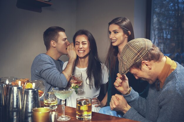 Foto de amigos alegres en el bar o en el pub comunicándose entre ellos