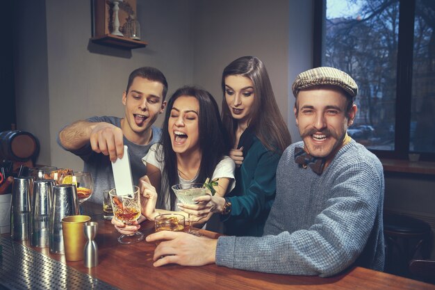 Foto de amigos alegres en el bar o en el pub comunicándose entre ellos