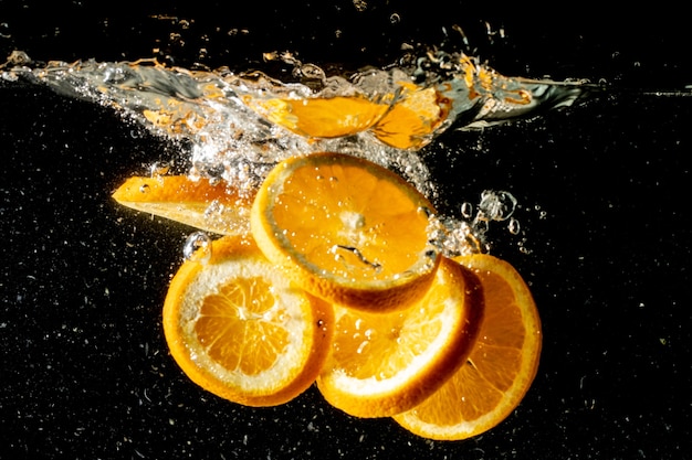 Foto de bodegón de rodajas de naranja cayendo bajo el agua y haciendo un gran chapoteo