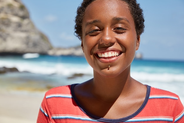 Foto gratuita foto brillante de hermosa niña feliz con piel oscura sana, amplia sonrisa