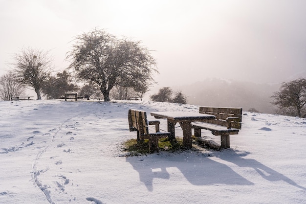 Foto gratuita foto brillante de un merendero con bancos cubiertos de nieve en la cima del monte aizkorri en gipuzkoa