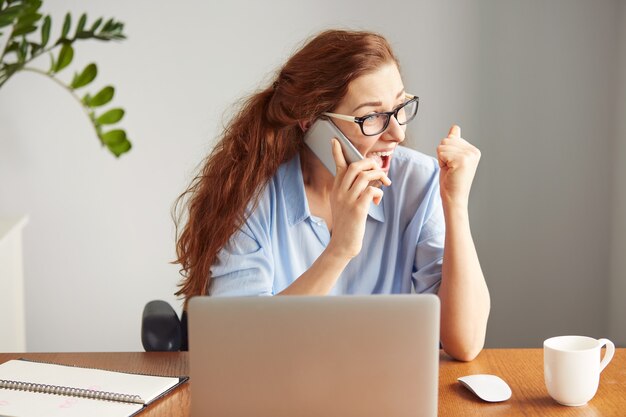 Foto de cabeza de una exitosa empresaria mirando emocionado hablando por teléfono celular