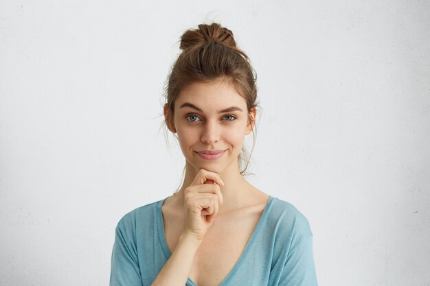 Foto de cabeza de una hermosa mujer con una mirada astuta que levanta la ceja y sostiene la mano en la barbilla con algunos planes complicados en su mente.