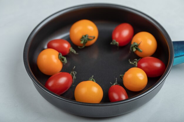 Foto de cerca de coloridos tomates cherry frescos en la sartén sobre fondo blanco. Foto de alta calidad