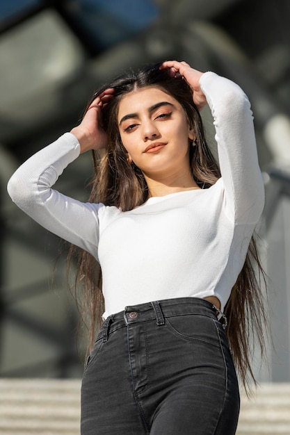 Foto de cerca de una joven en la calle estirando su cabello Foto de alta calidad