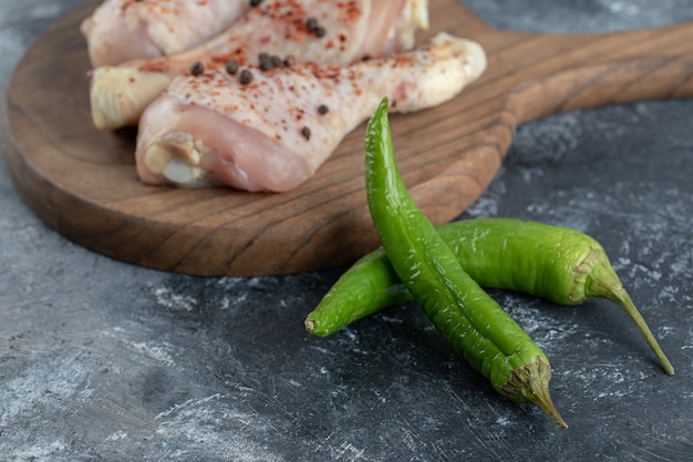 Foto de cerca de pimiento verde y muslos de pollo crudo. sobre fondo gris.