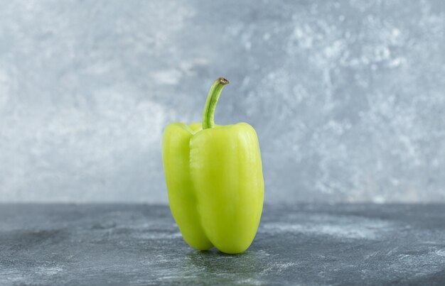 Foto de cerca de pimiento verde orgánico sobre fondo gris.