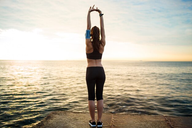 Foto de chica joven y bella fitness hace ejercicios deportivos con mar