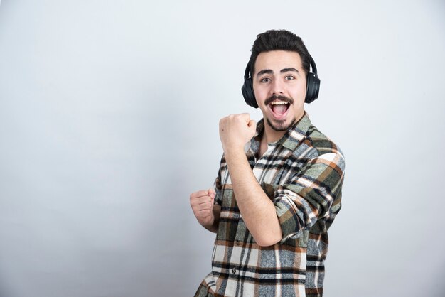 Foto de chico guapo en auriculares cantando una canción y bailando.