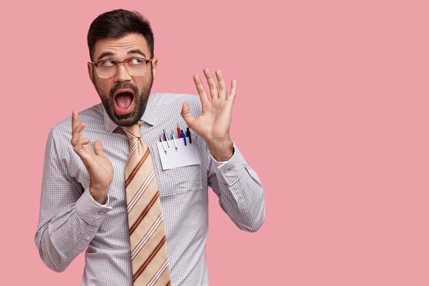 La foto de un chico guapo sorprendido exclama en voz alta, hace gestos con las manos, nota algo asombroso hacia arriba, tiene una expresión divertida