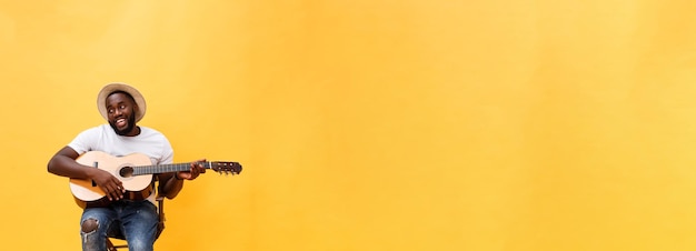 Foto gratuita foto completa de un hombre artístico emocionado tocando su guitarra aislado en un fondo amarillo