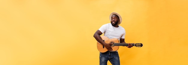 Foto completa de un hombre artístico emocionado tocando su guitarra en una suite informal aislada en el respaldo amarillo