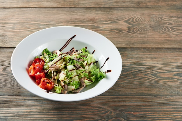 Foto de deliciosa ensalada con pollo decorado con tomates y salsa en la mesa de madera copyspace delicadeza sabroso apetito menú de hambre restaurante café almuerzo cena concepto.