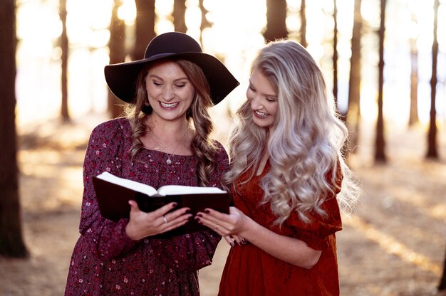 Foto de dos hembras jóvenes posando con un libro en el bosque, humor otoñal