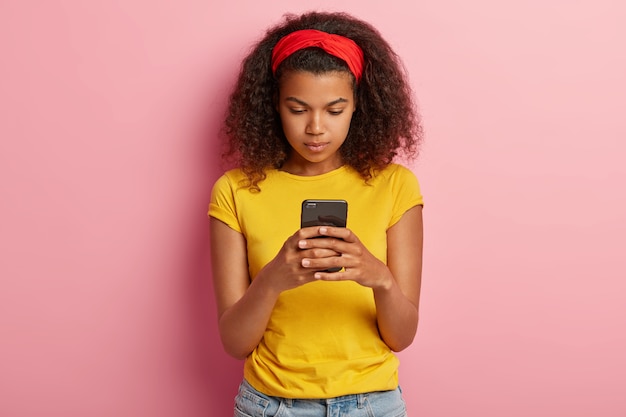 Foto de encantadora adolescente con pelo rizado posando en camiseta amarilla