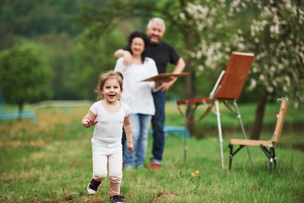 Foto enfocada. La abuela y el abuelo se divierten al aire libre con su nieta. Concepción de la pintura